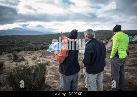 MONTE KILIMANJARO, Tanzania: Una guida ti indicherà la strada per l'escursione di quel giorno dal campo Shira 1 verso la vetta della montagna in lontananza sul monte Kilimanjaro. Foto Stock