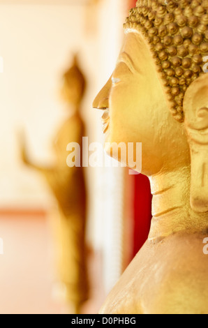 VIENTIANE, Laos - Golden statue del Buddha (Siddharta Gautama) a un Wat (Tempio buddista) in Vientiane, Laos. Questa statua è in stile cambogiano. La messa a fuoco è sulla statua in primo piano con profondità di campo ridotta. Foto Stock