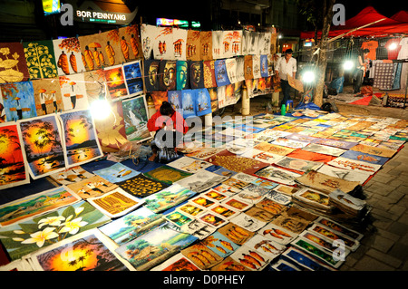 VIENTIANE, Laos - una donna guarda dopo la sua vendita di stallo paintaings, disegni e altre illustrazioni steso a terra su su schede al mercato notturno sul Quai Fa Ngum sulle rive del Mekong in Vientiane, Laos. Foto Stock