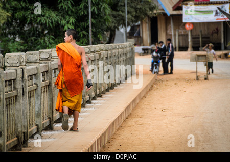 NONG KHIAW, Laos - un giovane buddista debuttante nel suo in arancione vesti passeggiate attraverso il ponte di Nong Khiaw, Laos. Foto Stock