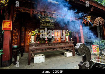 HANOI, Vietnam - fumo blu dal bruciando incenso aleggia attraverso l'aria al di fuori di Quan Thanh tempio di Hanoi. Il tempio taoista risale al XI secolo e si trova vicino al Lago Ovest. Foto Stock