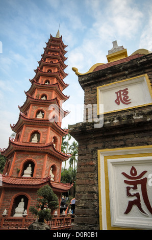 HANOI, Vietnam: Il cancello d'ingresso e la torre della Pagoda Tran Quoc si trovano in posizione dominante sull'isolotto Golden Fish del Lago Occidentale. Il complesso del tempio, trasferito in questo sito nel 1615, presenta elementi architettonici tradizionali buddisti vietnamiti. Queste strutture rappresentano il duraturo patrimonio architettonico di uno dei templi buddisti più antichi del Vietnam. Foto Stock