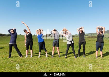 Donne stretching prima di andare su un cross country eseguito attraverso i terreni agricoli e il paese di lato. Foto Stock