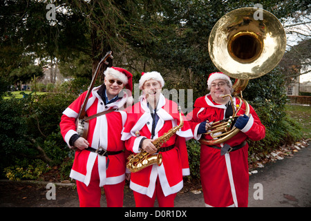 Tre uomini in santa claus costumi riproduzione di musica a Bury St Edmunds mercatino di natale, Suffolk REGNO UNITO Foto Stock