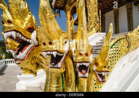 LUANG PRABANG, Laos — la naga dorata (Re Cobra) adorna le scale di Haw Pha Bang (Cappella del Palazzo) presso il Museo del Palazzo reale di Luang Prabang, Laos. La cappella ornata, situata nell'angolo nord-orientale dei giardini del museo, mostra l'architettura tradizionale del Laos e il simbolismo buddista. Foto Stock