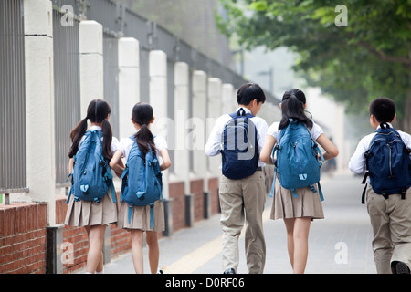 Vista posteriore di scolari in uniforme sulla strada per la scuola Foto Stock