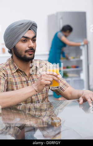 Uomo con in mano un bicchiere di succo di arancia Foto Stock