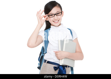Piuttosto schoolgirl regolando gli occhiali con libri e zainetto Foto Stock