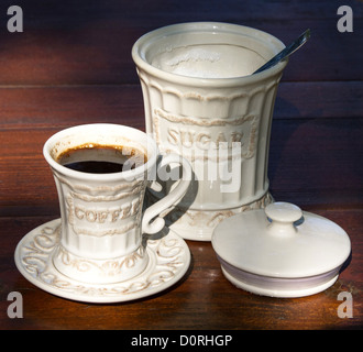 Tazza di caffè e jar con lo zucchero sul tavolo di legno in giardino Foto Stock