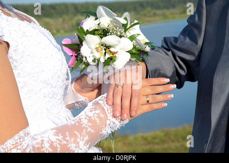 Le mani e gli anelli con bouquet di nozze Foto Stock