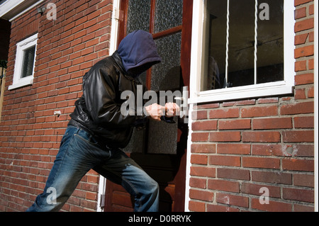 Un ladro che cerca di entrare in una casa dalla porta posteriore Foto Stock