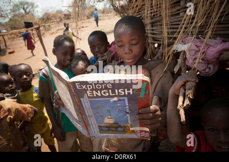 I bambini del villaggio eccitato per leggere un libro di testo inglese insieme nella Luangwa, Zambia, Sud Africa. Foto Stock