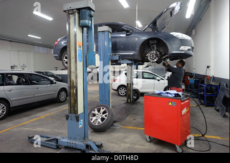 Auto controllo meccanico di un auto sollevata su un sollevatore idraulico Foto Stock