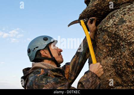 Lo scalatore martelli a gancio nella roccia Foto Stock