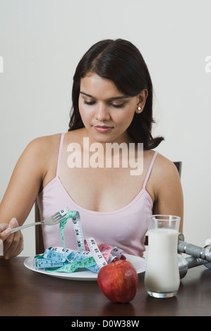 Donna che mantiene un nastro di misurazione con una forcella Foto Stock