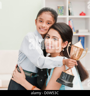 Ragazza con un trofeo e abbracciando la madre Foto Stock