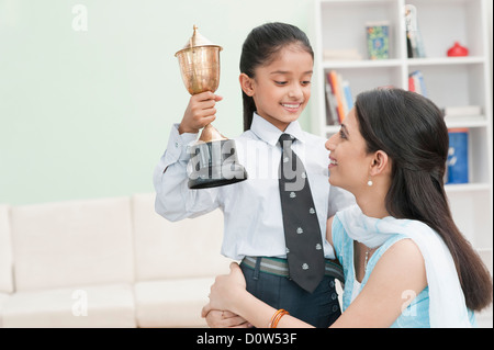 Ragazza che mostra un trofeo alla sua madre Foto Stock