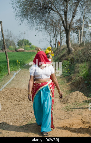 La donna a camminare su una strada sterrata, Farrukh Nagar, Gurgaon, Haryana, India Foto Stock