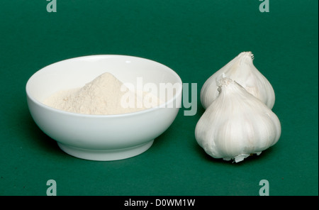 Aglio schiacciato in polvere e tutto il capi di aglio. Sfondo verde Foto Stock