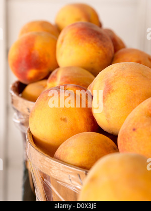 Fresche pesche raccolte in cesti. Mature le pesche ammucchiati in cestelli attendono gli acquirenti a un mercato sul ciglio della strada. Foto Stock