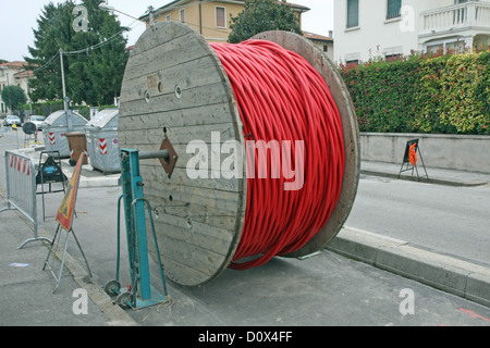 Bobine di enorme di rosso ad alta tensione del cavo di alimentazione nel mezzo della strada Foto Stock