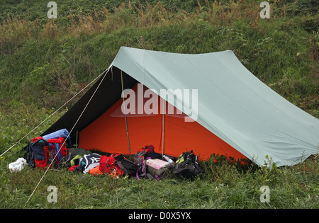 Tenda arancione con molti zaini depositato di fronte all'ingresso Foto Stock