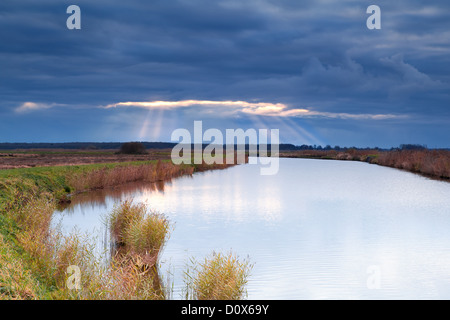 Raggi di sole attraverso offuscato la tempesta cielo sopra il fiume Foto Stock