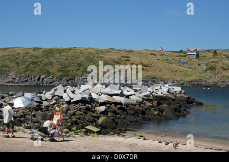 Un artista sulla spiaggia sulla isola di Monhegan, Maine, guardando verso la vicina isola di Manana Foto Stock