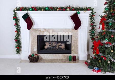 Il gas naturale camino decorato con albero, ornamenti, calze, basket e regali Foto Stock