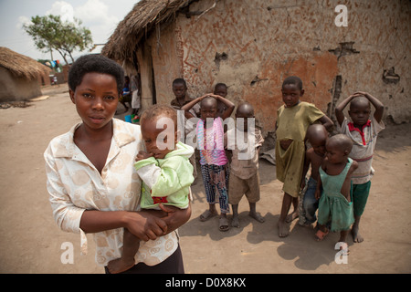 Una giovane madre detiene il suo bambino fuori dalla sua casa a Kasese, Uganda, Africa orientale. Foto Stock