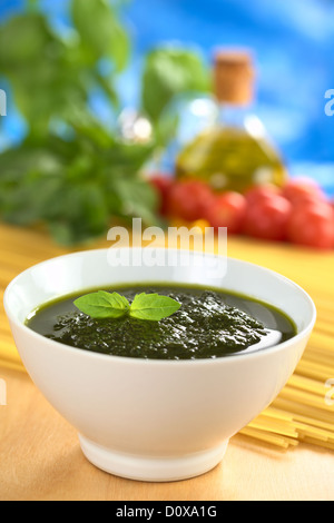 Pesto fresco fatto di basilico, aglio e olio di oliva in una ciotola e guarnito con una foglia di basilico Foto Stock