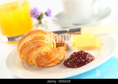 La prima colazione continentale con croissant, confettura di fragole, burro, succo d'arancia e caffè (messa a fuoco selettiva, concentrarsi sull'inceppamento) Foto Stock