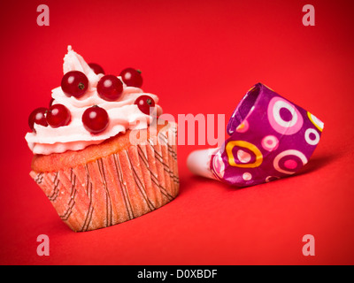 Muffin con ribes rosso e la parte di fissaggio per soffiare su sfondo rosso Foto Stock