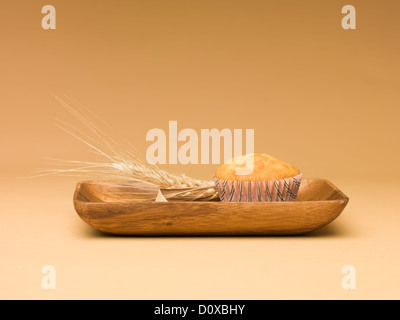 Muffin semplice sul vassoio in legno con chicco di grano oltre a sfondo beige Foto Stock