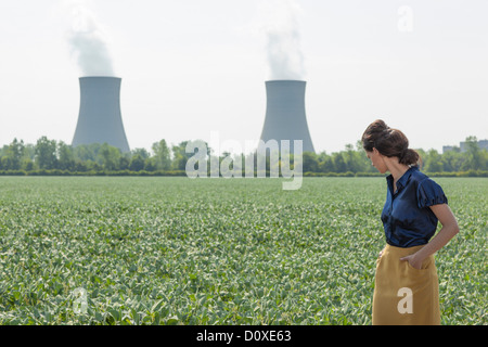 La donna nel fagiolo di soia archiviato guardando dietro alla centrale nucleare Foto Stock