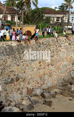 Persone sedersi sulla parte esterna della parete in pietra del Forte di Galle. Foto Stock
