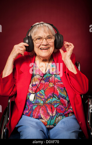 Senior donna ascoltare musica sulle cuffie Foto Stock