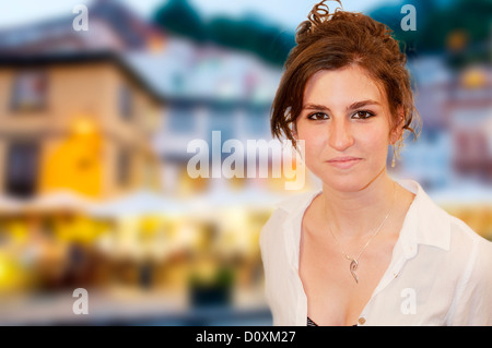 Ritratto di giovane donna sorridente e guardando la telecamera, con Cudillero in background. Asturias, Spagna. Foto Stock
