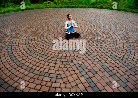 Donna meditando in pavimentazioni di circoli di pietra Foto Stock