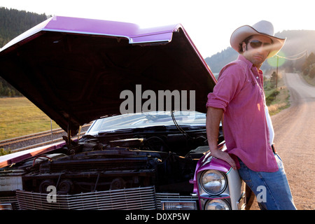 Uomo appoggiato a auto d'epoca con cappa su Foto Stock