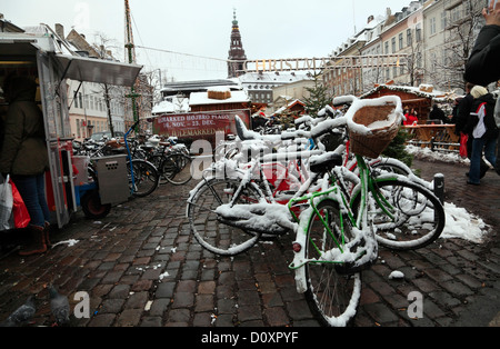 Coperta di neve biciclette presso il mercatino di Natale a Højbro Plads (Hoejbro Square) su Strøget (Stroeget) di Copenhagen, Danimarca. Neve e granite. Foto Stock