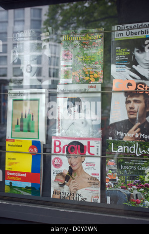 Riviste per la vendita sul display nella finestra giornalai, Dusseldorf, Germania. Foto Stock