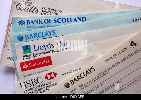 Selezione di assegni tratti su banche diverse con il pagamento in set di slittamento su sfondo bianco Foto Stock