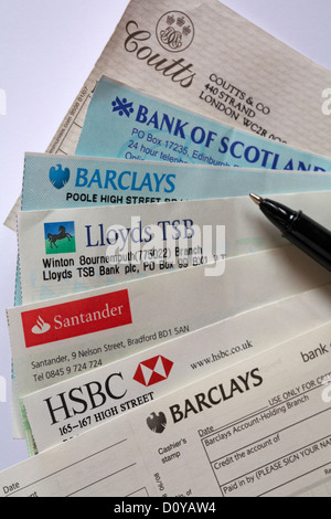 Selezione di assegni tratti su banche diverse con il pagamento in set di slittamento su sfondo bianco Foto Stock