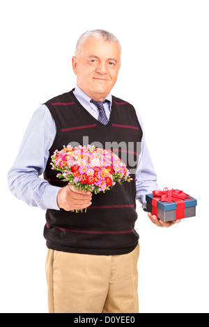 Un sorridente uomo maturo tenendo un dono e un mazzo di fiori isolati su sfondo bianco Foto Stock