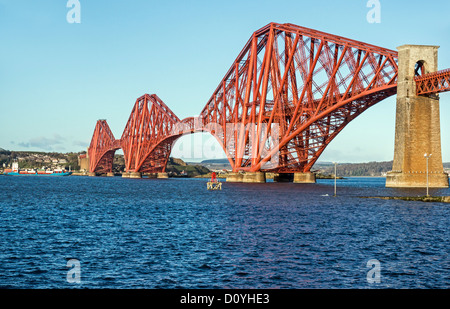 Dipinto recentemente Ponte di Forth Rail visto da South Queensferry in Scozia con una nave portacontainer da Grangemouth passando attraverso Foto Stock