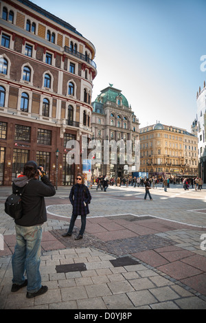 Una giovane donna pone la sua fotografia scattata in Stephansplatz, Vienna, ornato di vecchi edifici dietro di lei. Foto Stock