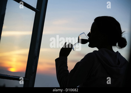 La donna beve il vino rosso al tramonto verso ovest Ho Devon Foto Stock