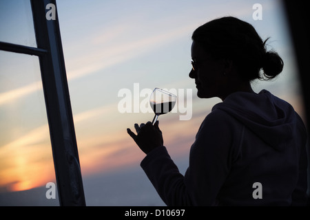 La donna beve il vino rosso al tramonto verso ovest Ho Devon Foto Stock