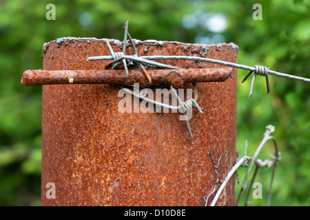 Rusty colonna con filo spinato con il focus impostato su di esso Foto Stock